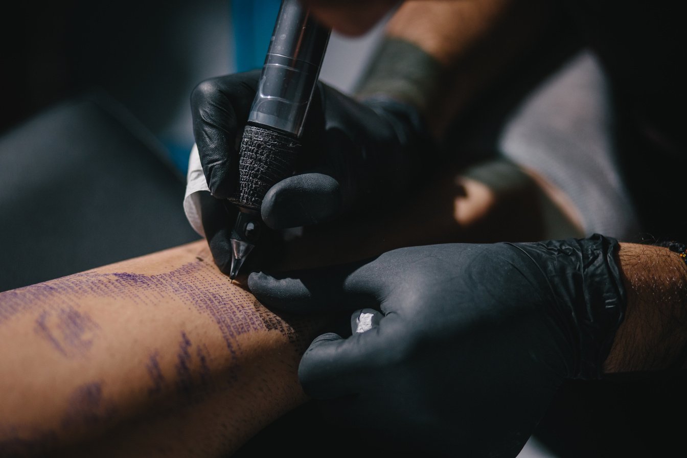 Tattoo artist working with tattoo machine on tattoo design